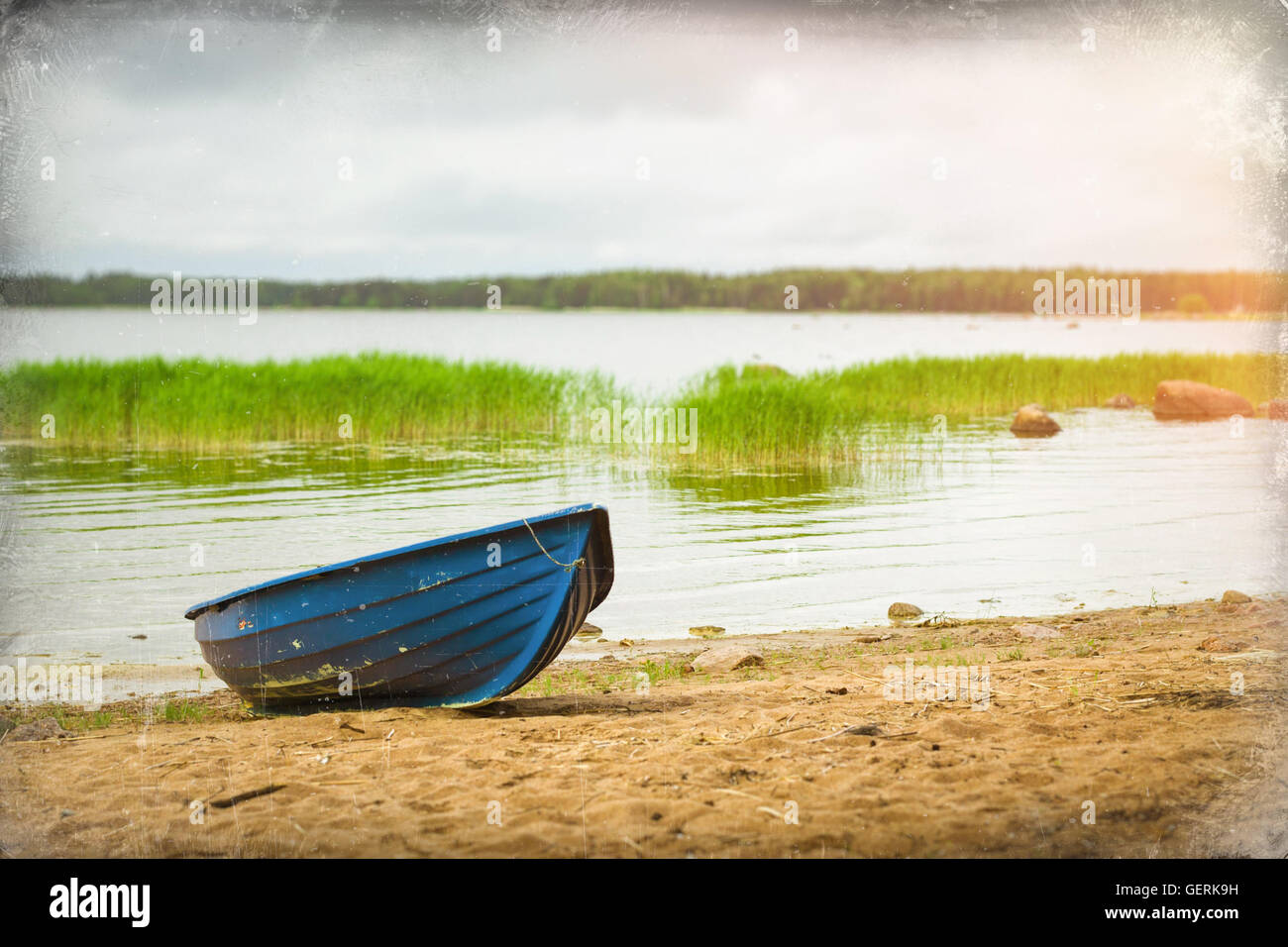 Blue rowing boat stands on a sandy shore in a quiet Bay of the Finnish Gulf. Area for summer camping in the woods. Hamina, Fin Stock Photo