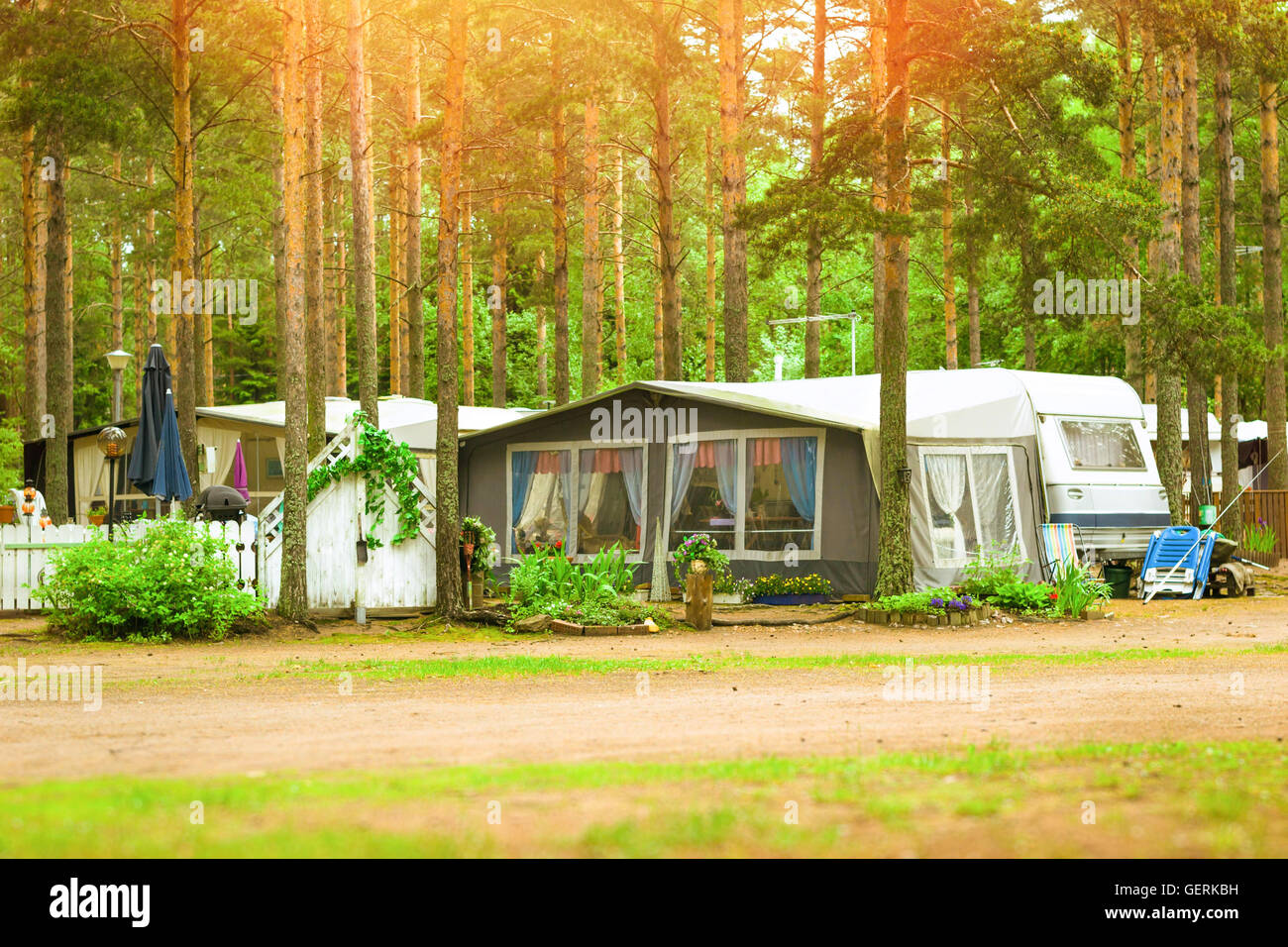 Summer outdoor recreation, Scandinavian vacation. Camping vans and tents parked in a wooded campsite among pine trees. Finland Stock Photo