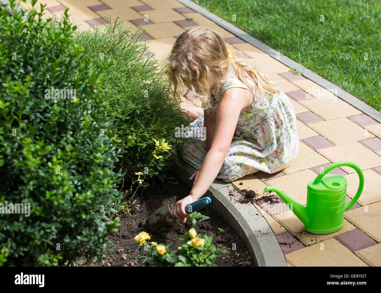 Little blonde girl planting flower in a garden Stock Photo - Alamy