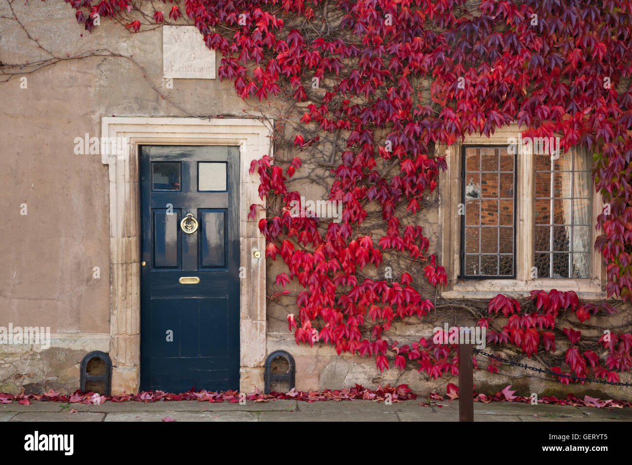 Virginia creeper frames the doorway of a house with a datestone of 1691 in Hallaton Stock Photo