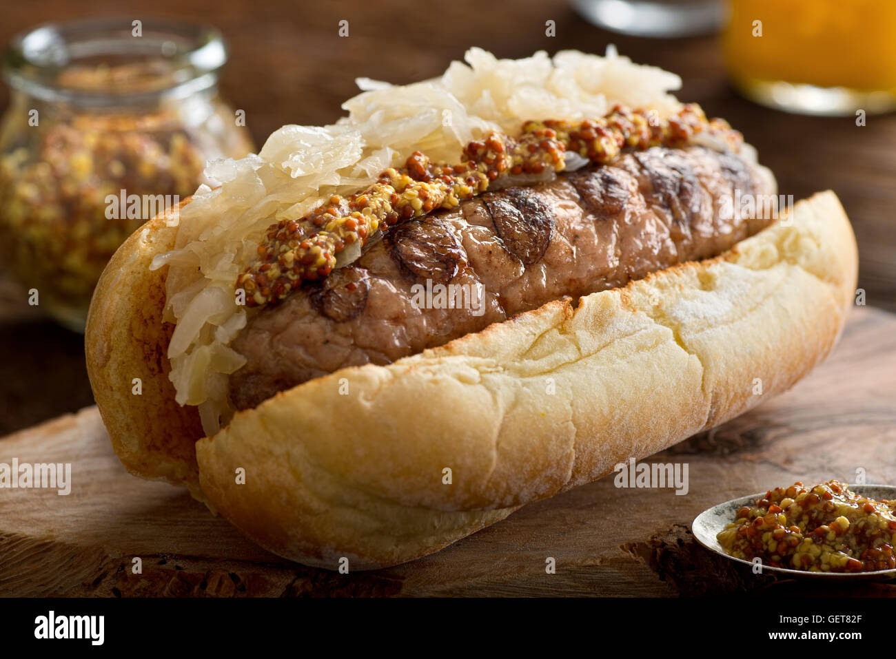 A delicious grilled sausage with sauerkraut and coarse mustard on a toasted hot dog bun. Stock Photo