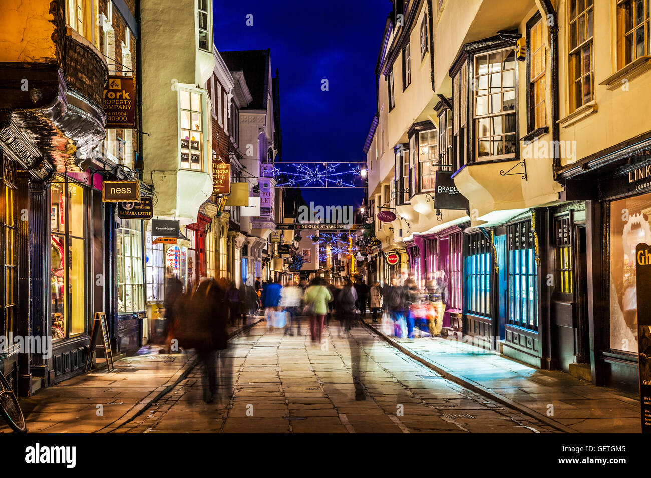 Christmas shoppers hurrying along the historic street of Stonegate in York at twilight. Stock Photo