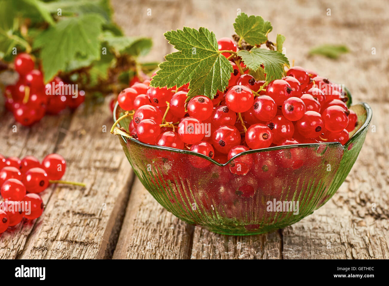 Red currant in glass bowl on wooden table Stock Photo