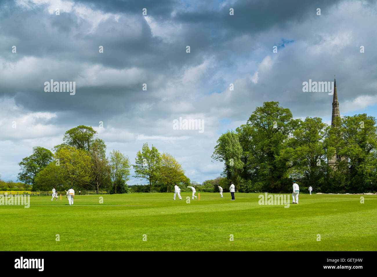 A cricket match on a village field under a stormy spring sky. Stock Photo
