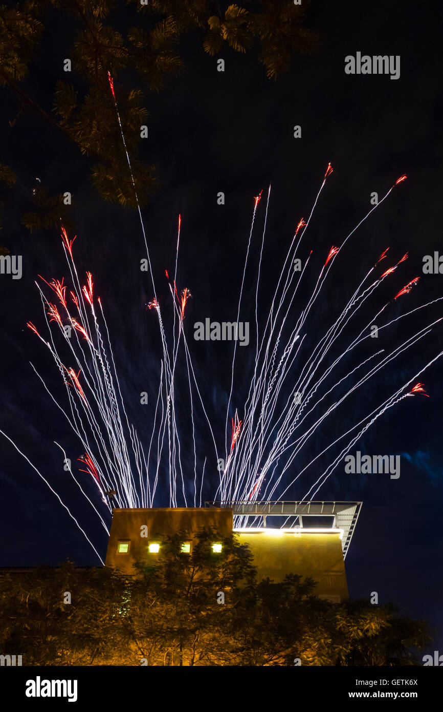 Multiple fireworks tracer trails above building Stock Photo