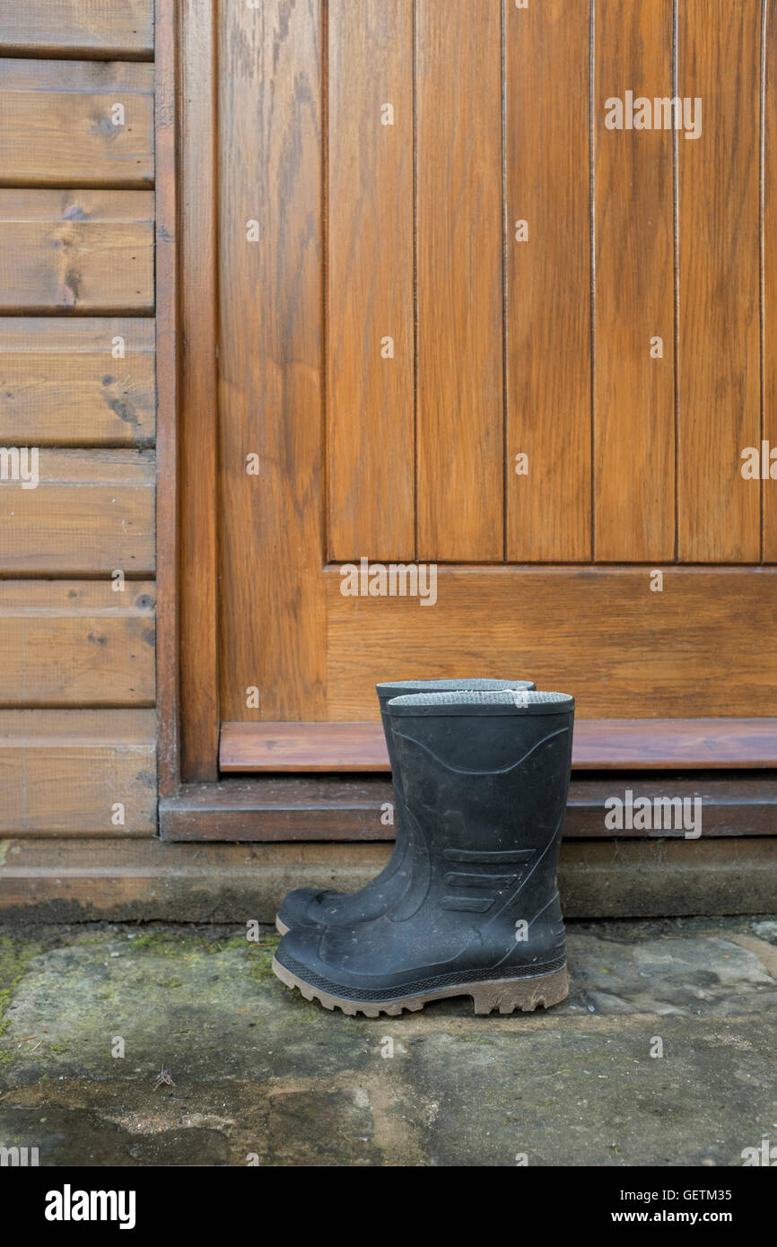 A pair of black wellington boots outside the front door of a house. Stock Photo