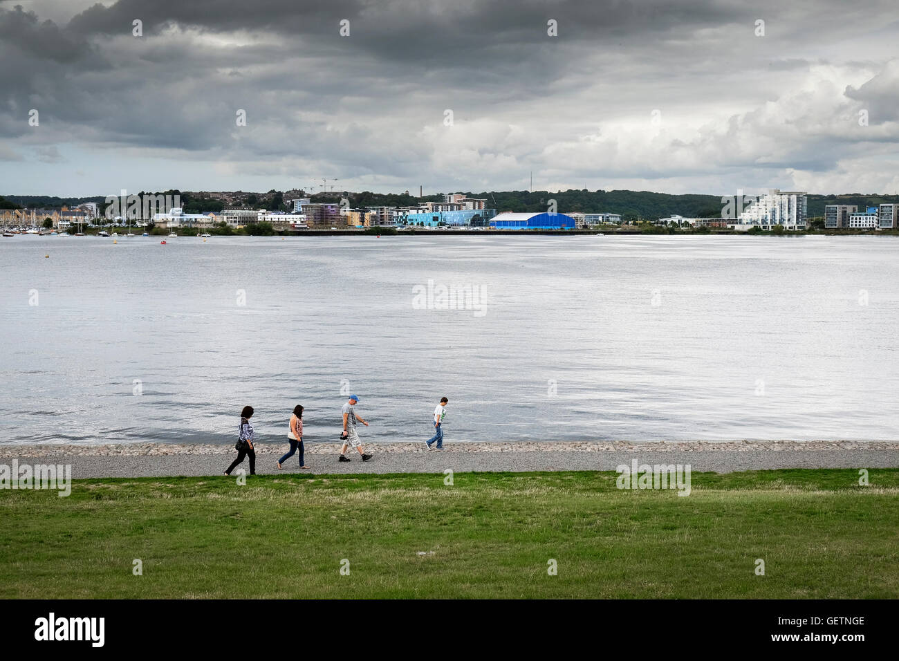 A family walking along the footpath on the barrage at Cardiff Bay. Stock Photo