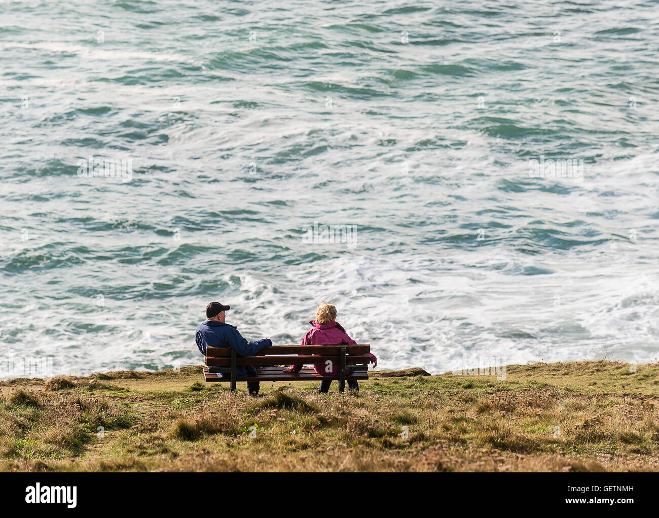 Two people sitting on a bench overlooking the sea Stock Photo - Alamy