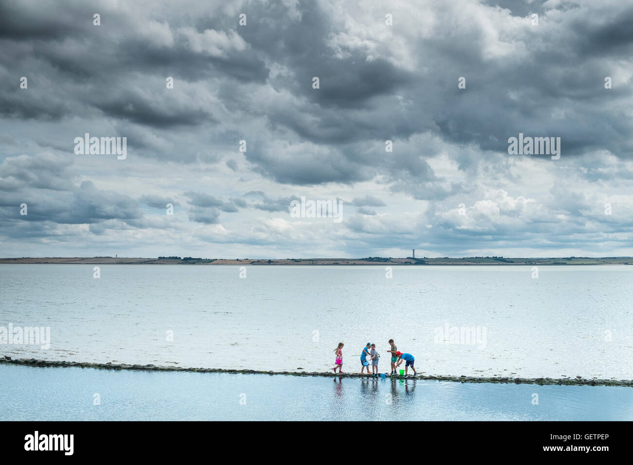 Children exploring on the foreshore at Canvey Island in Essex. Stock Photo