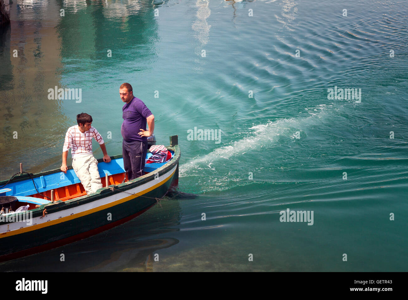 Mediterranean boatmen heading out of harbour. Stock Photo