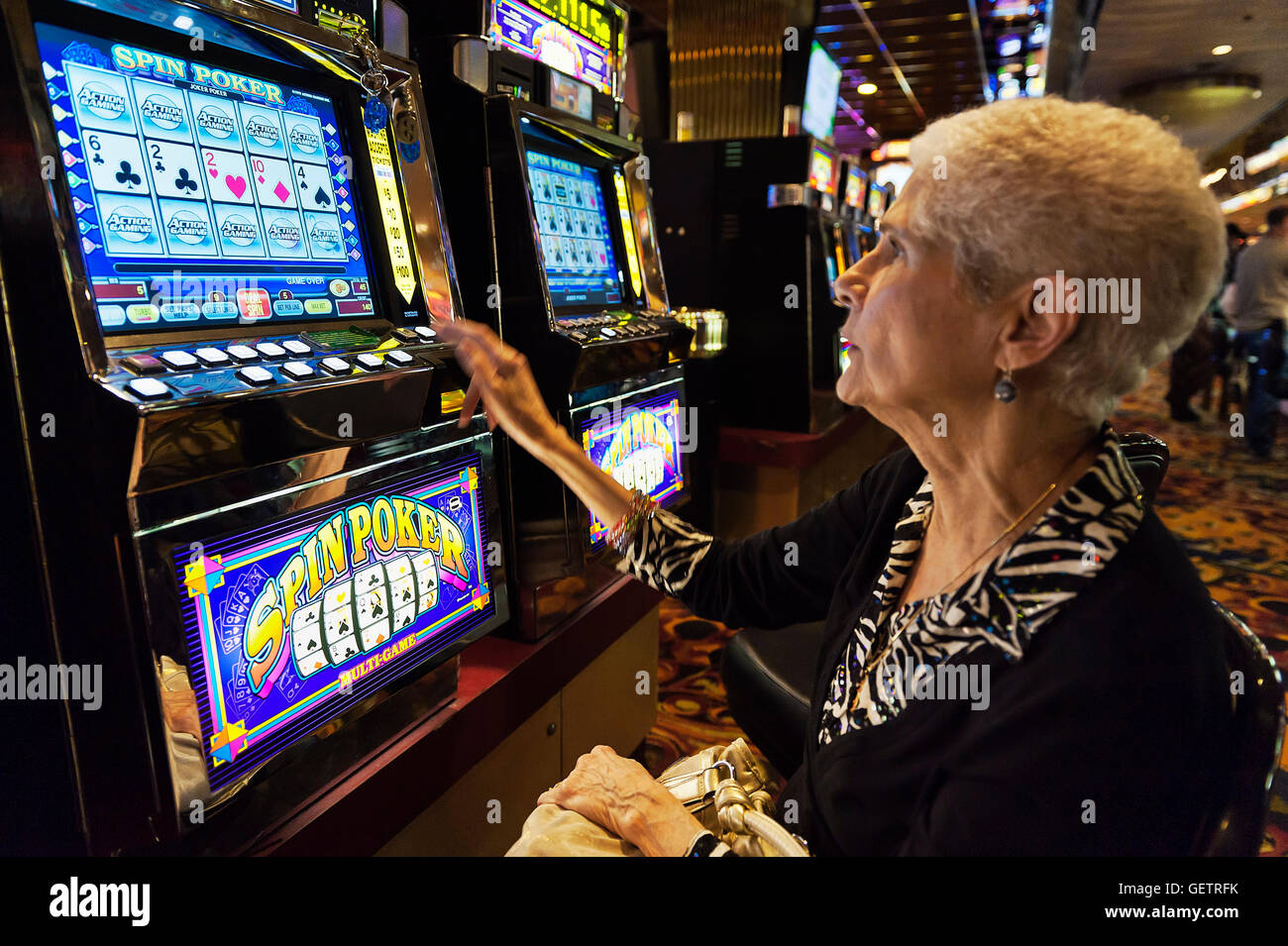 Senior woman playing a slot machine. Stock Photo