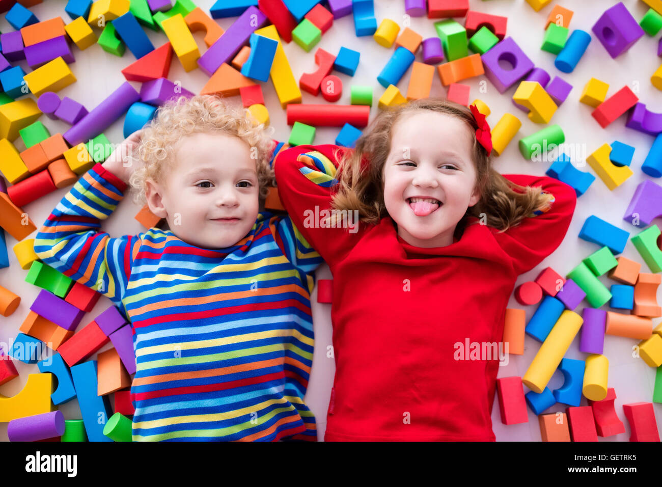 Happy preschool age children play with colorful plastic toy blocks ...