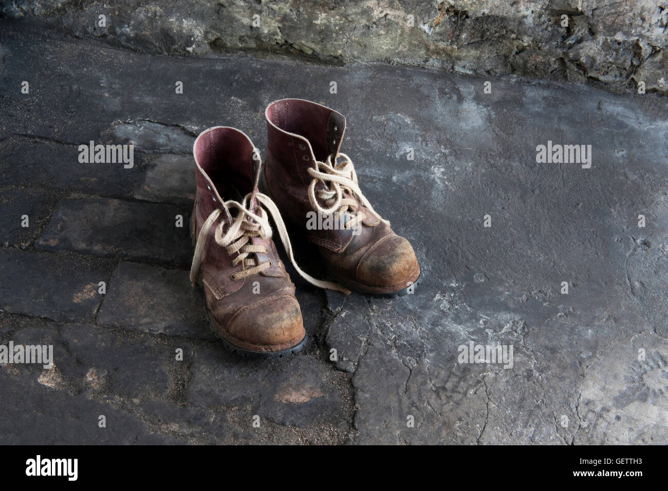A pair of old leather work boots on a barn floor. Stock Photo