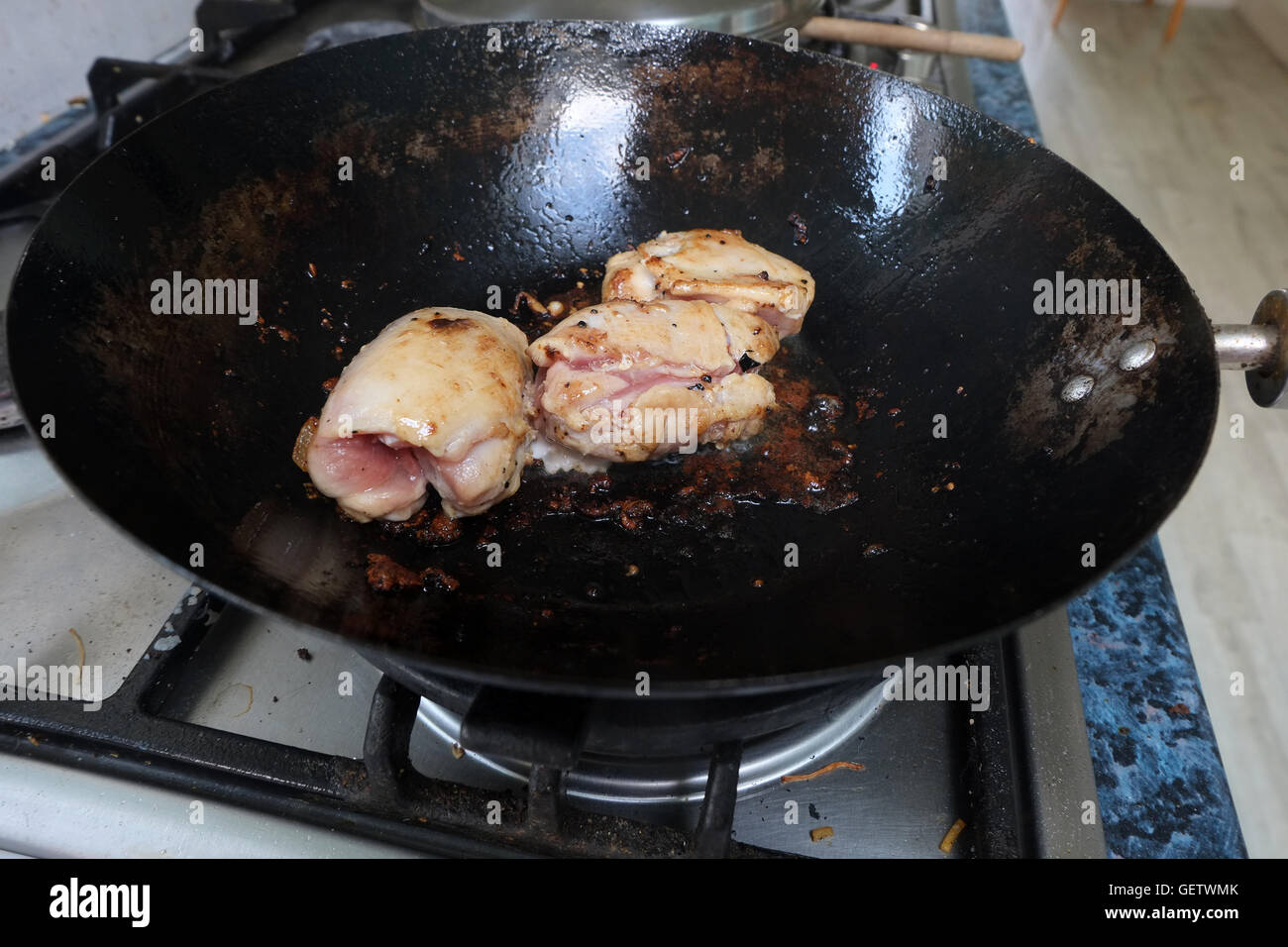Cooking chicken in a wok on a modern gas cooker Stock Photo Alamy