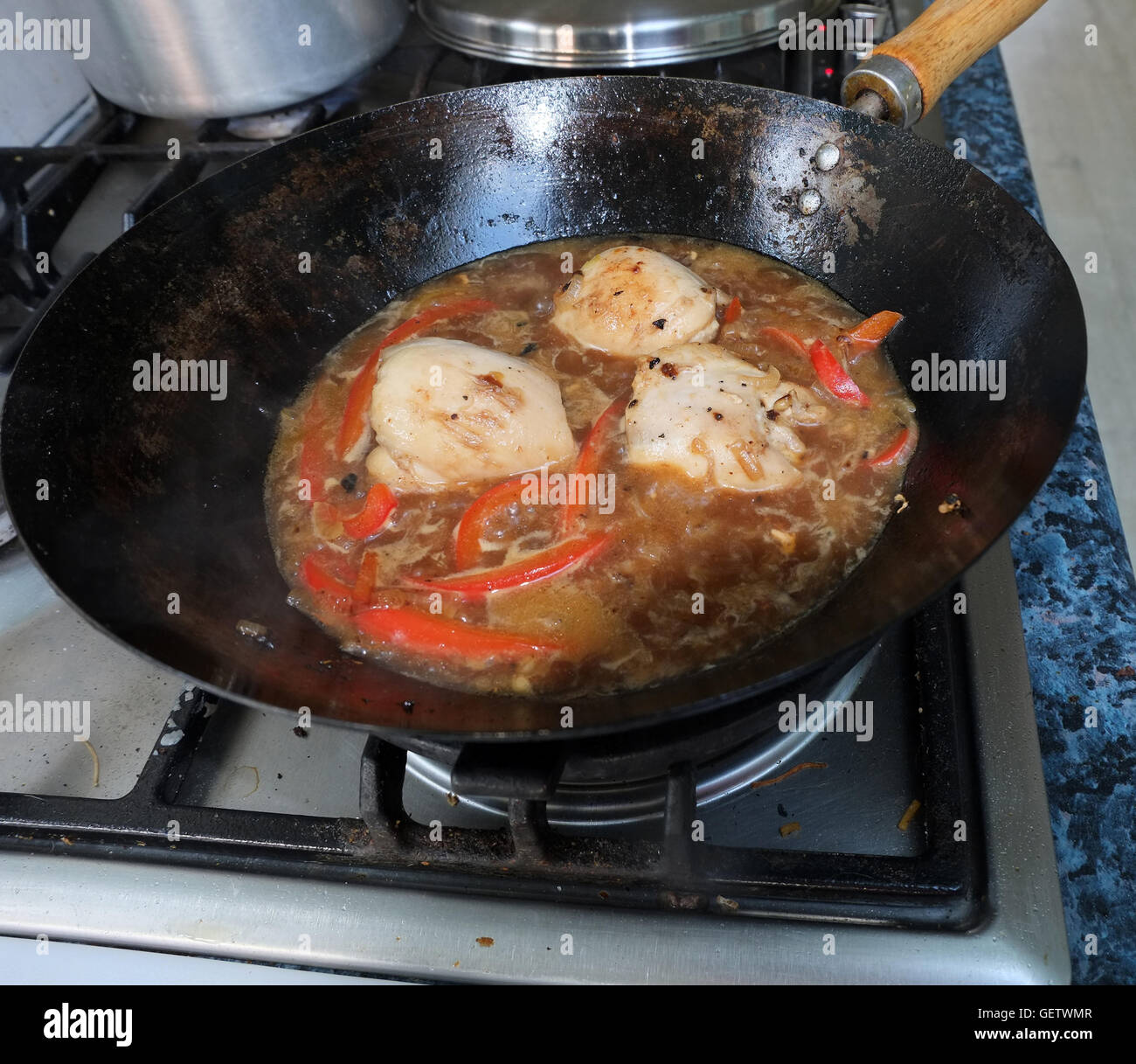 Cooking chicken in a wok on a modern gas cooker Stock Photo Alamy