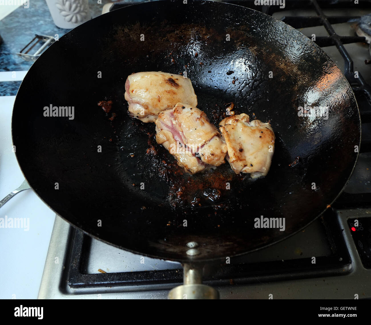 Cooking chicken in a wok on a modern gas cooker Stock Photo Alamy