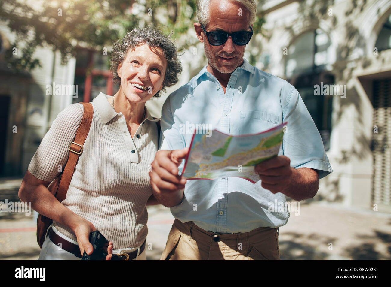 Portrait of senior tourist couple in town using a map. Mature man and woman using map while sightseeing. Stock Photo