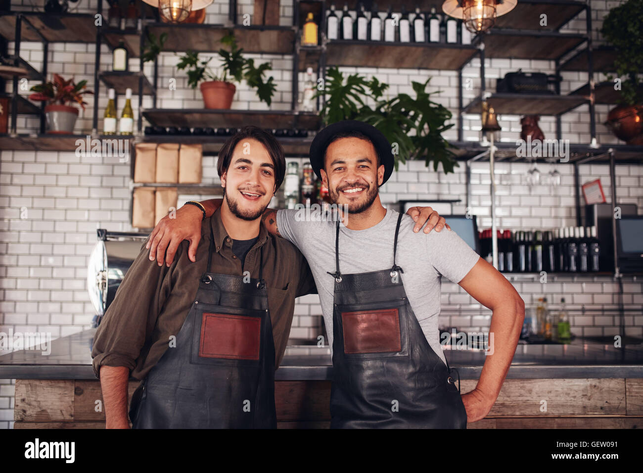 Portrait of two young coffee shop partners standing together at the counter. Happy young male bartenders. Stock Photo