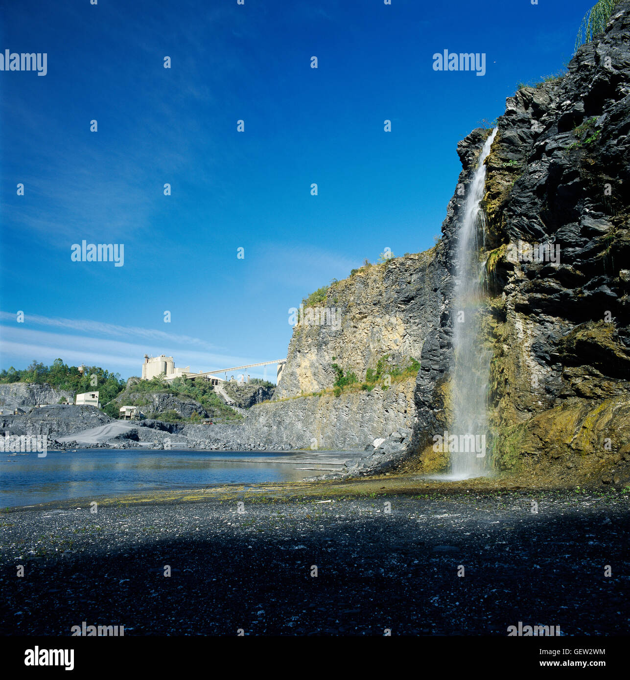 Waterfall in limestone quarry with cement plant in background Stock Photo Alamy