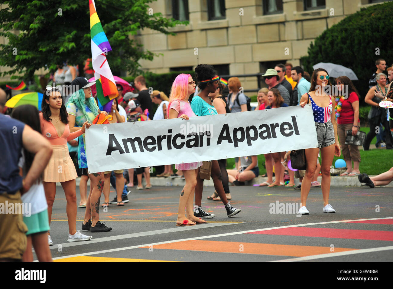 People holding an American Apparel banner during a Pride parade in the