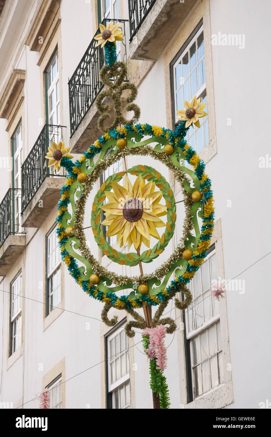 A sunflower motif at the centre of an Easter decoration made of tinsel, suspended above an alleyway in Alfama, Lisbon, Portugal. Stock Photo