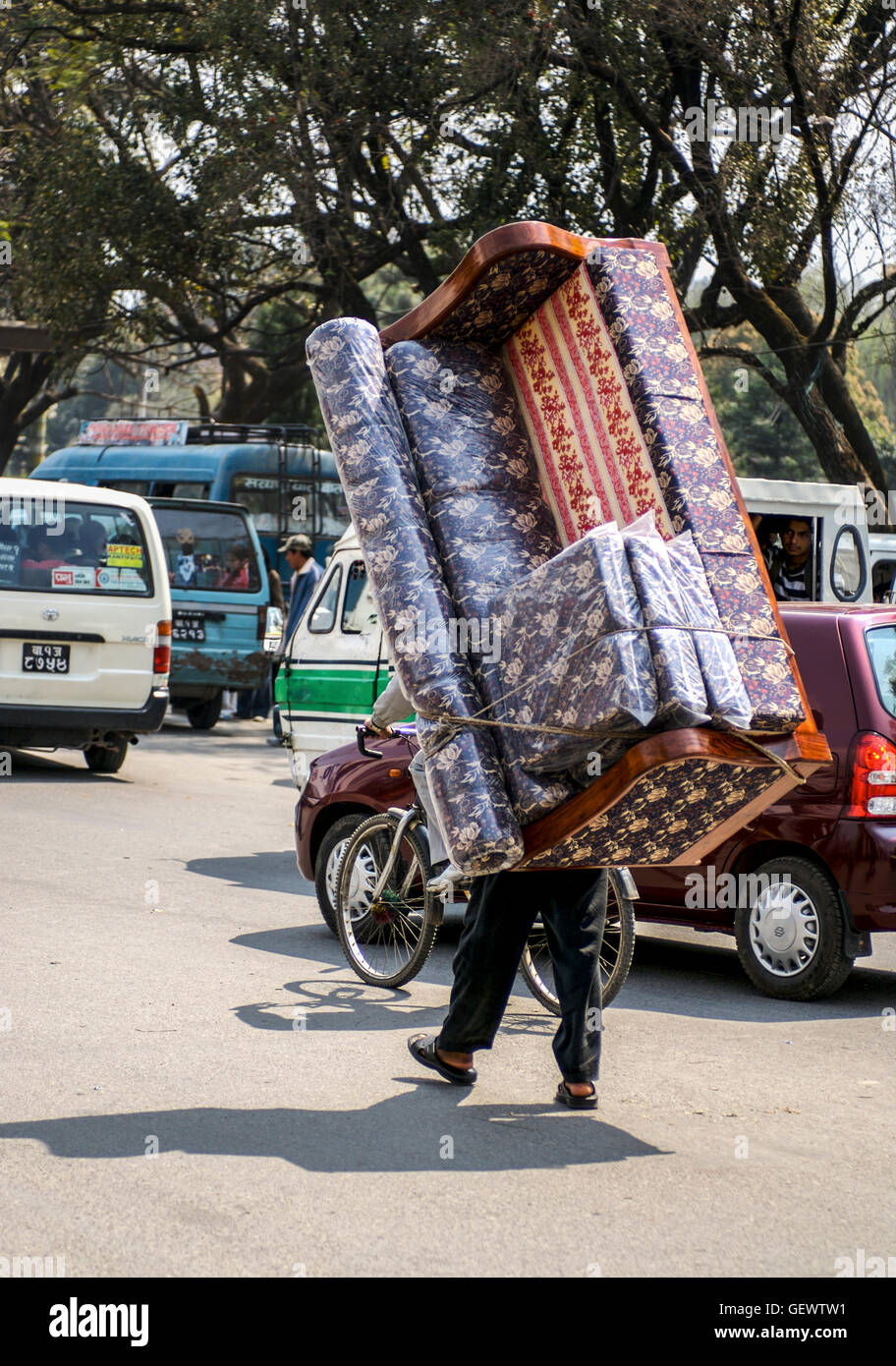 Man carrying a settee on his back in a busy street in Kathmandu. Stock Photo