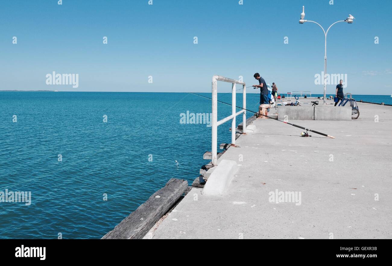 Coogee,WA,Australia-November 13,2015:Fisherman on the Coogee Beach jetty with pelicans and the Indian Ocean in Coogee, Western Australia. Stock Photo
