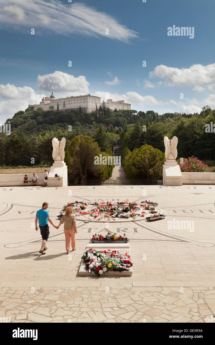 A couple leaving The Polish Cemetery at Monte Cassino past the wreaths of flowers with the abbey in the distance. Stock Photo