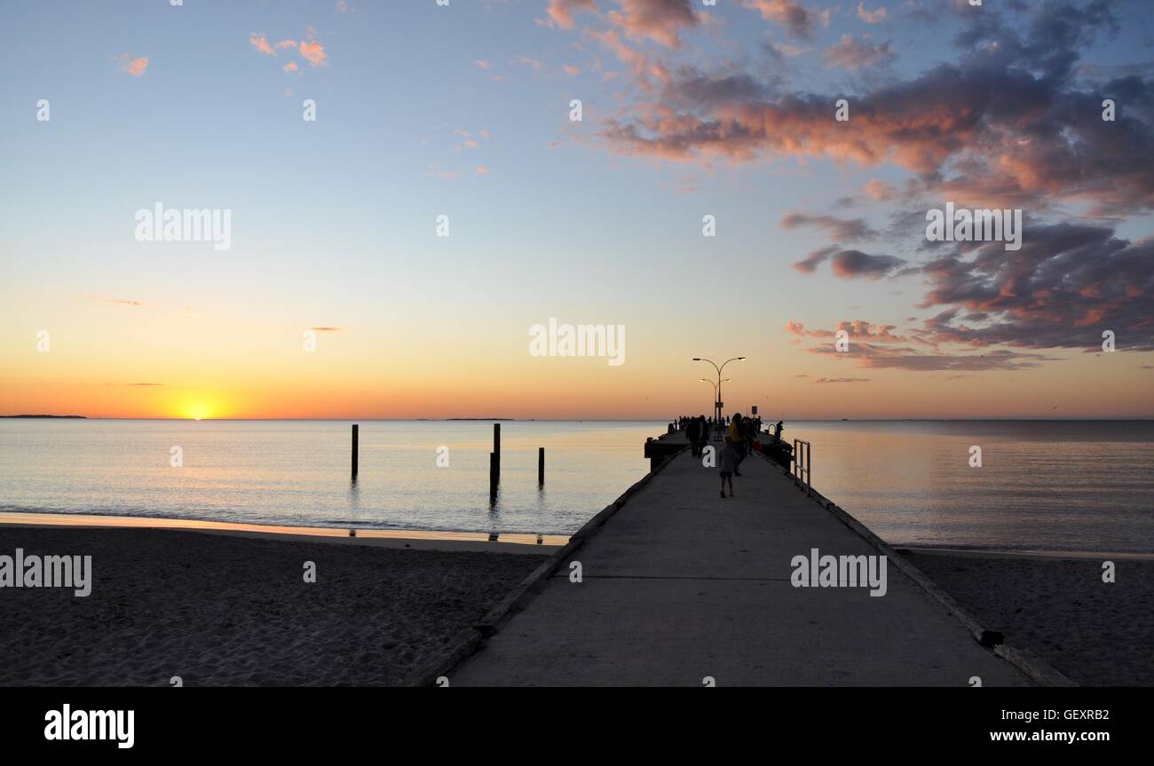 Jetty in diminishing perspective with the calm Indian Ocean waters and orange sunset at Coogee Beach in Coogee,Western Australia Stock Photo