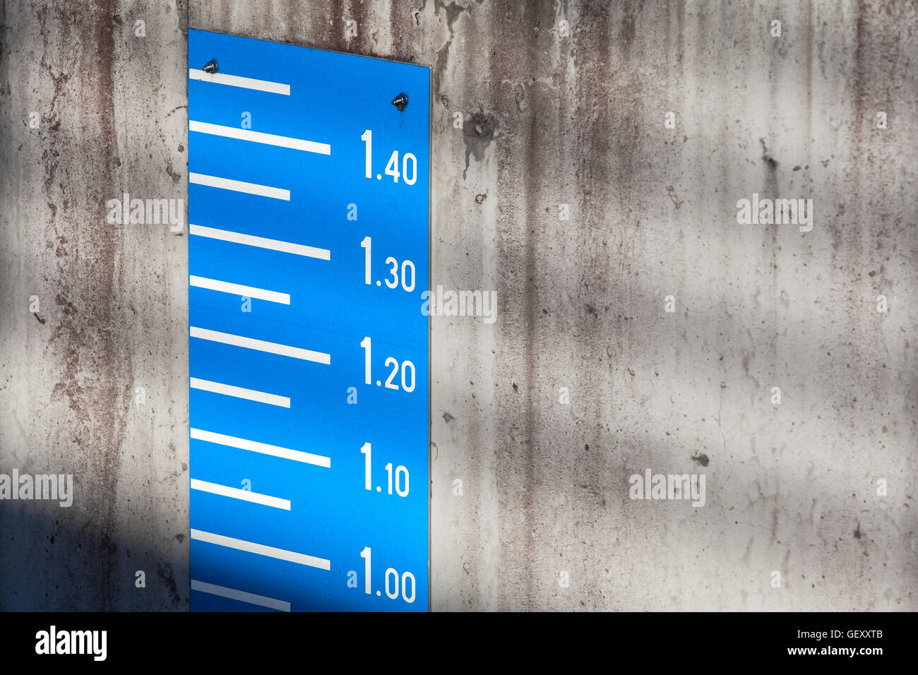 Blue tide level measurement scale on concrete mooring wall in port Stock Photo