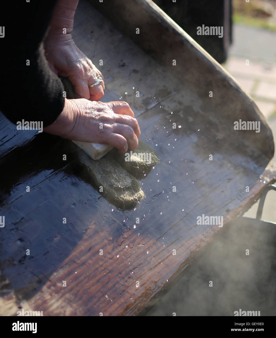 Hands of the elderly woman washing in the old wooden board Stock Photo