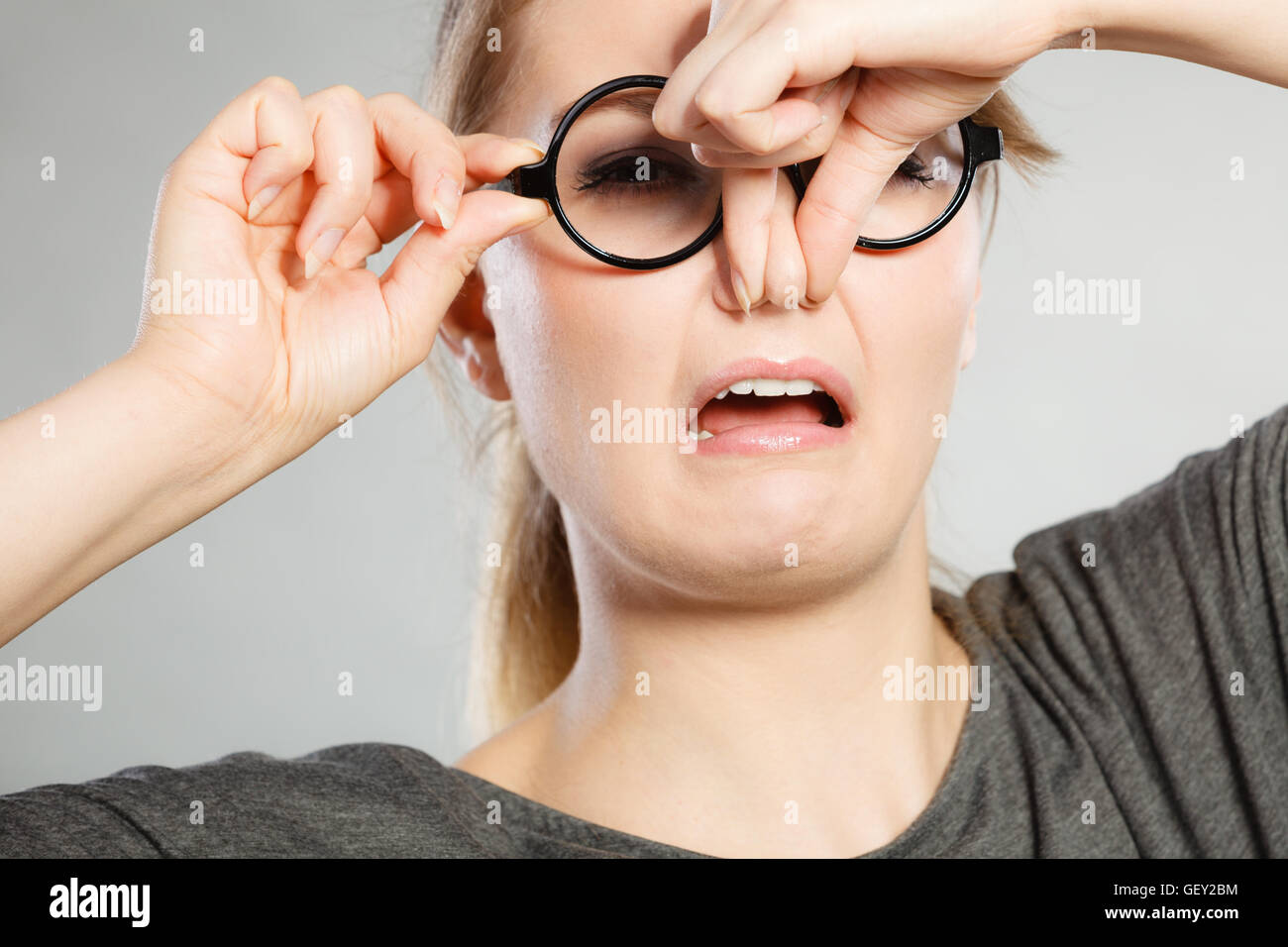 Bad smell concept. Young woman feels disgust pinches her nose with
