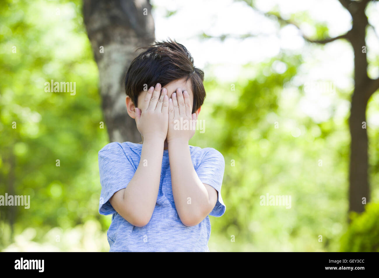 Little Chinese boy covering his eyes in woods Stock Photo - Alamy