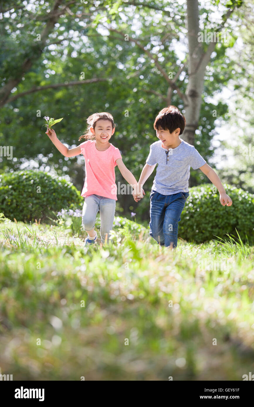 Happy Chinese children holding hands running in woods Stock Photo - Alamy