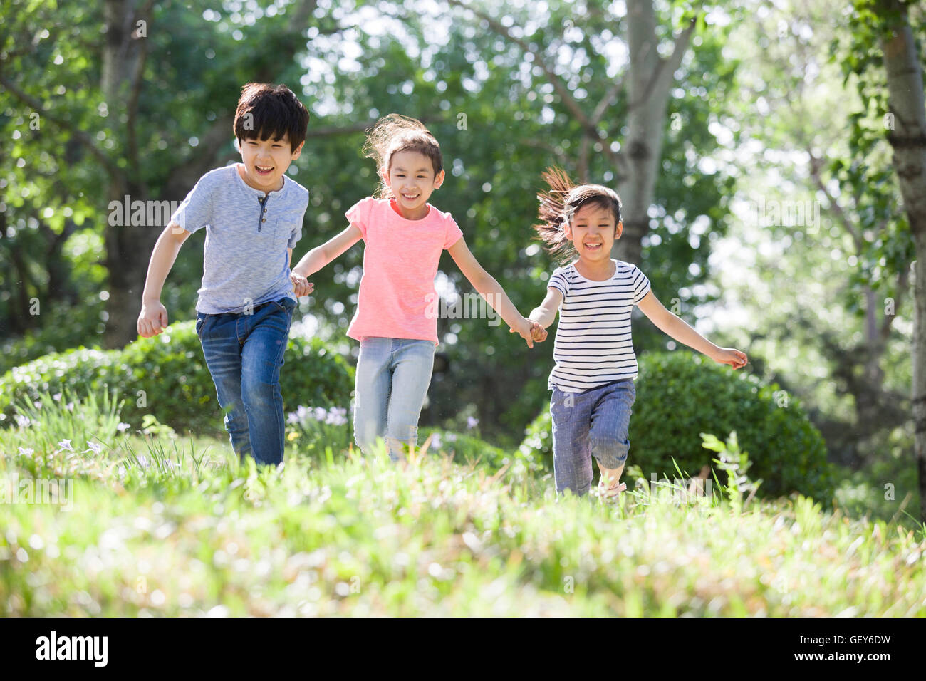 Happy Chinese children holding hands running in woods Stock Photo - Alamy
