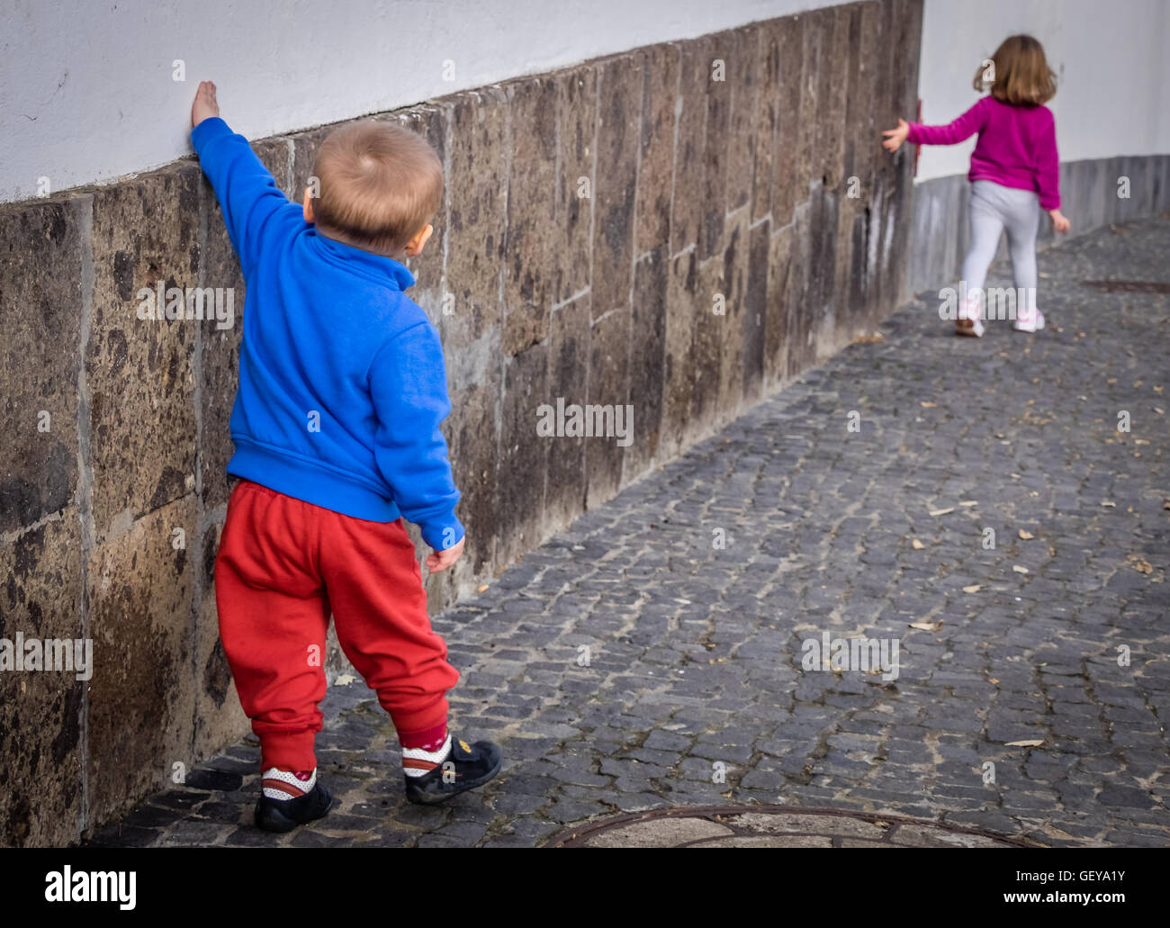 Little kids - brother and sister walking along the home wall in Spain Stock Photo