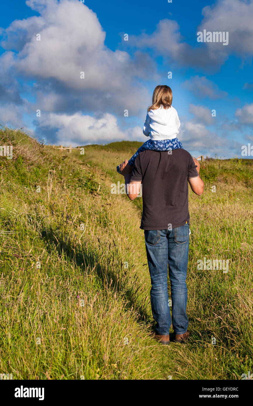 Father and daughter. Daddy carrying little girl. Dad giving female kid a shoulder ride. Parenting family concept. Stock Photo