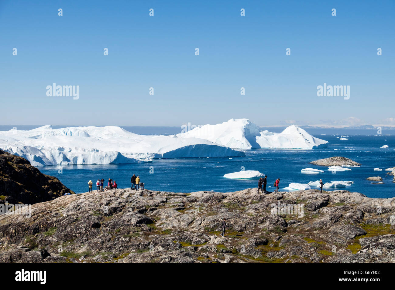 People on a hiking trail at Nakkaavik viewpoint overlooking Disko Bay with icebergs from Ilulissat Icefjord offshore. Ilulissat Greenland Stock Photo