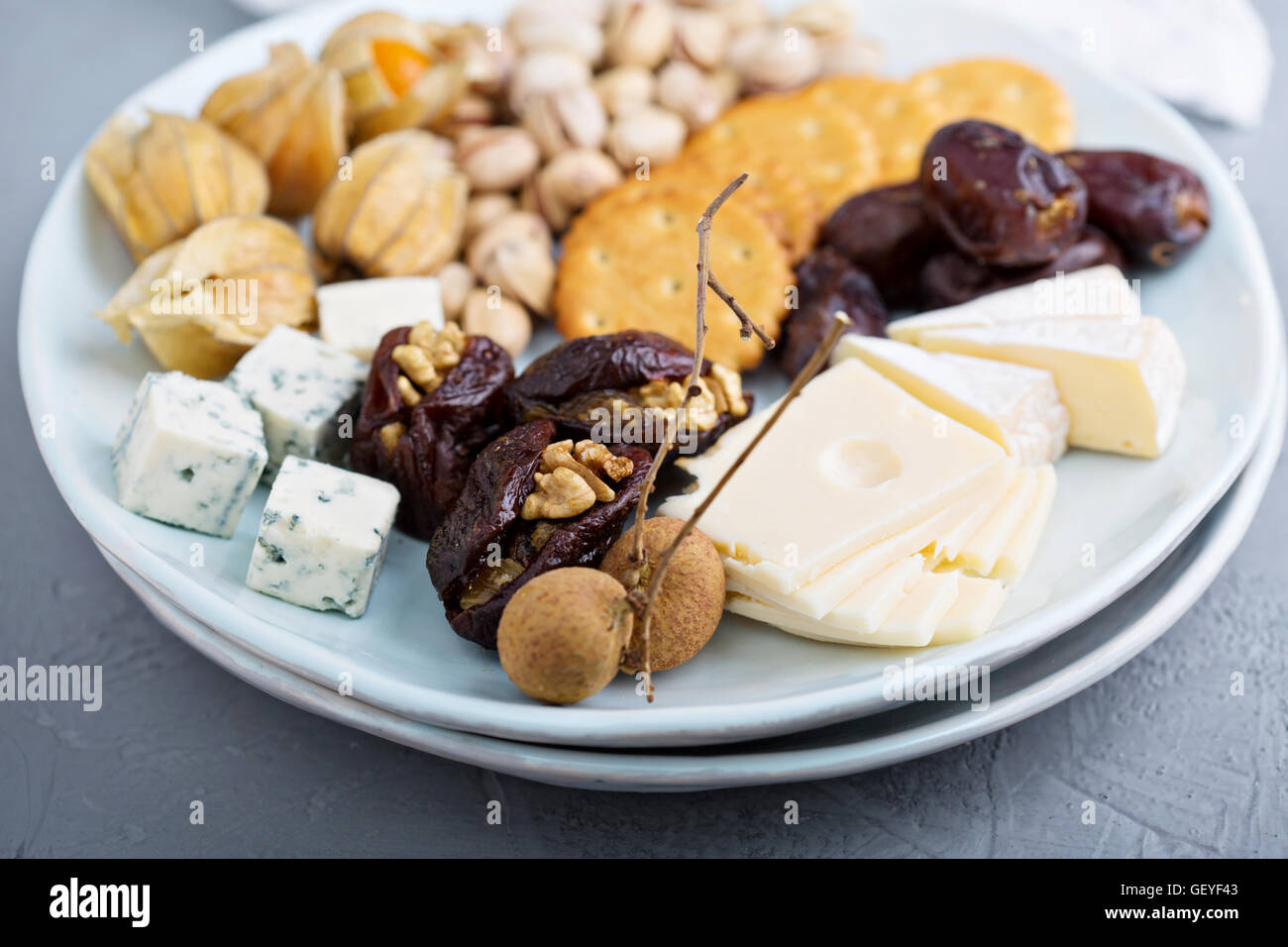 Cheese plate with crackers, dates and nuts Stock Photo