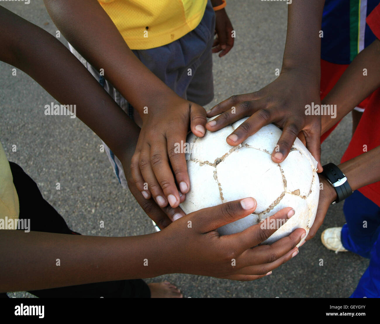 Children's hands holding an old soccerball, South Africa Stock Photo