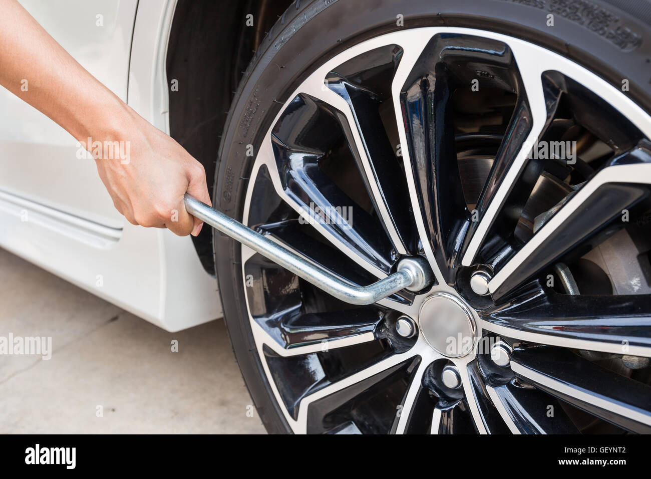 Hands disassembling a modern car wheel (steel rim) with a lug wrench