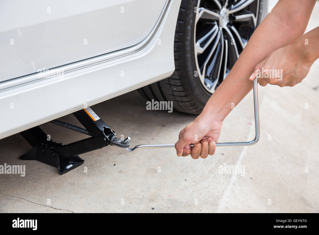 Hand lifting a car with spanner jack-screw Stock Photo