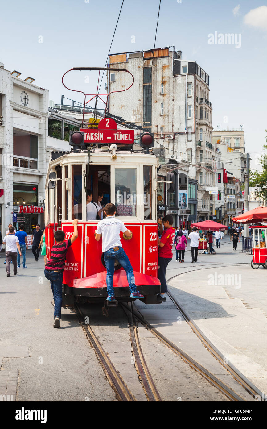 Istanbul, Turkey - July 1, 2016: Vintage red tram goes on Taksim square in Istanbul, boys ride for free on the bumper Stock Photo