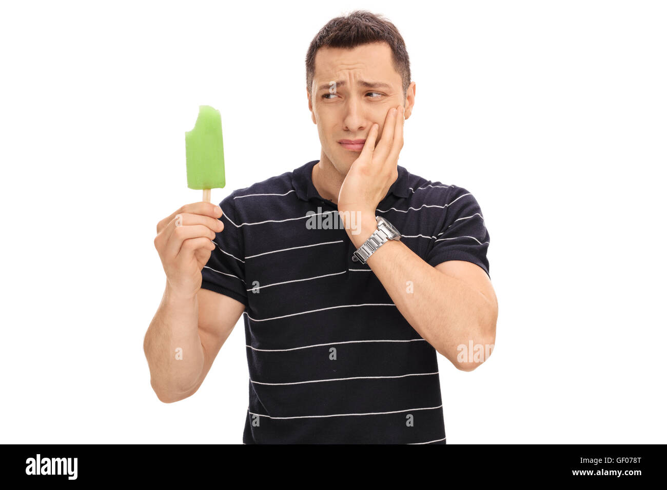 Young guy experiencing a tooth ache from eating ice cream isolated on