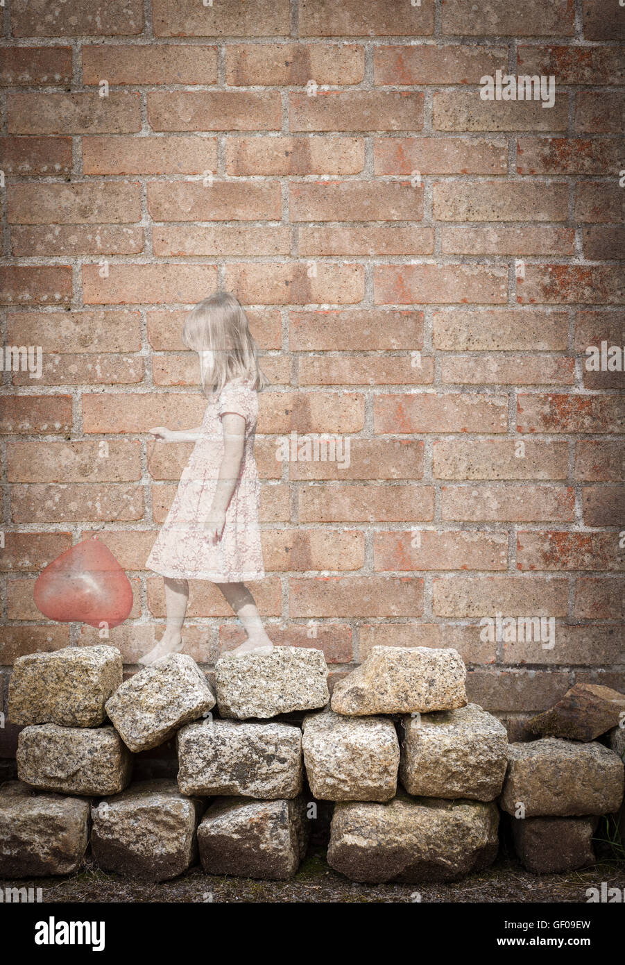 Pretty little girl holding red heart balloon. Ethereal opaque with grunge brick wall. Love childhood memories loneliness concept Stock Photo