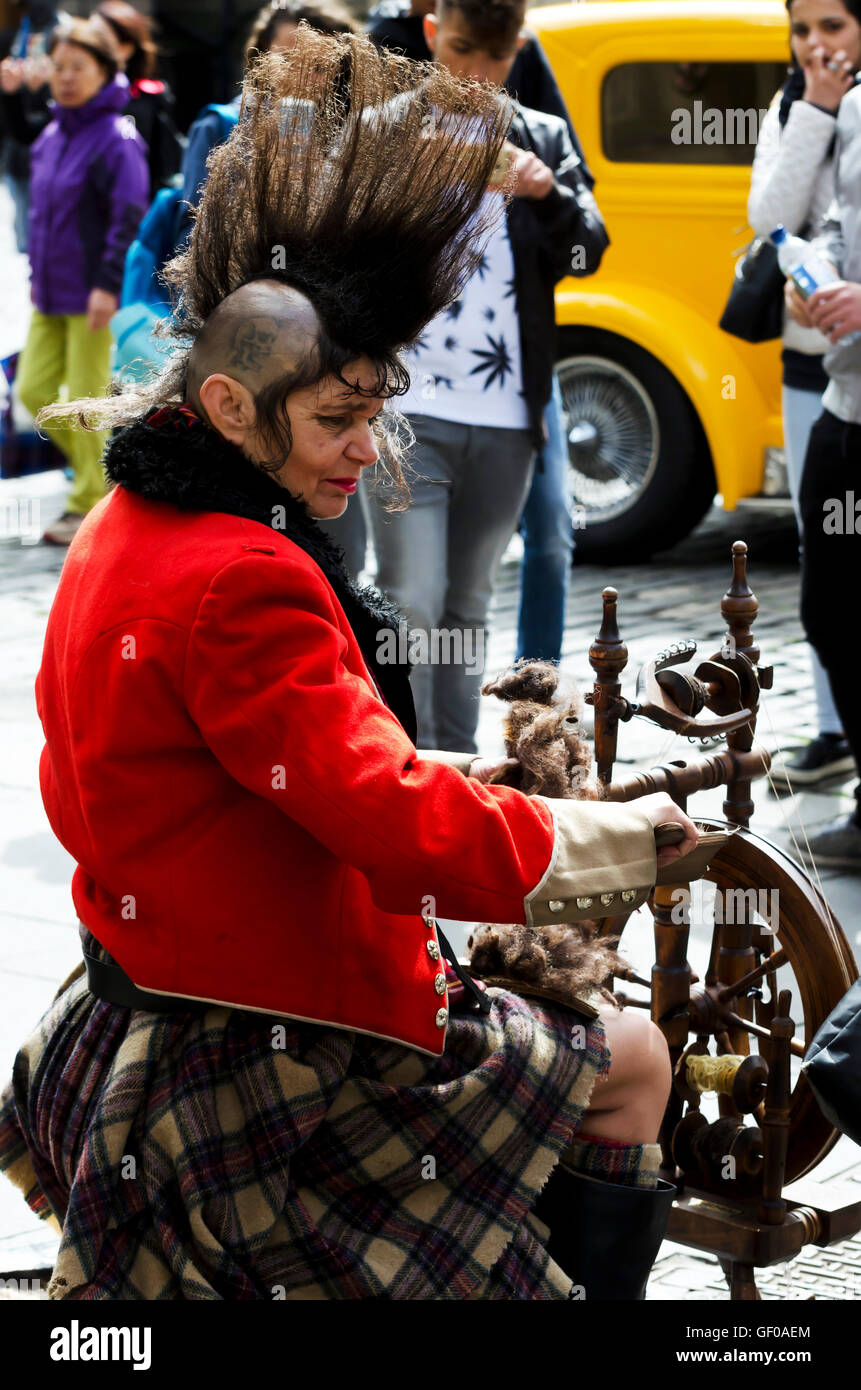 Middle-aged punk-style woman with a spinning wheel in the Royal Mile, Edinburgh. Stock Photo