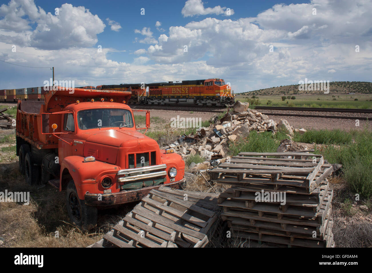 1954 International Harvester tipper truck R190 with pallets and train speeding past in background Stock Photo