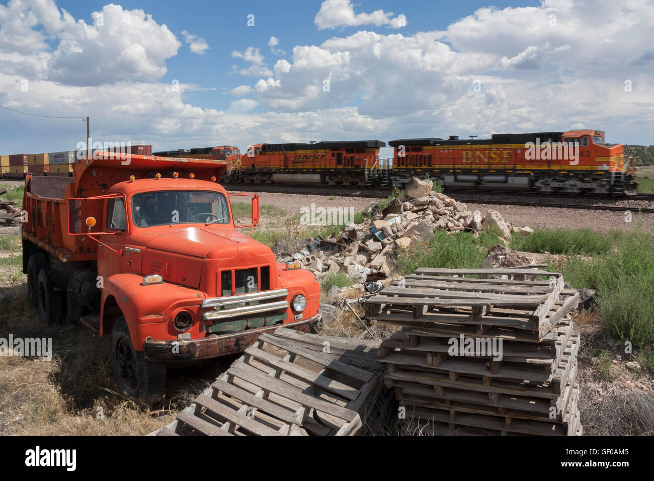 1954 International Harvester tipper truck R190 with pallets and train speeding past in background Stock Photo