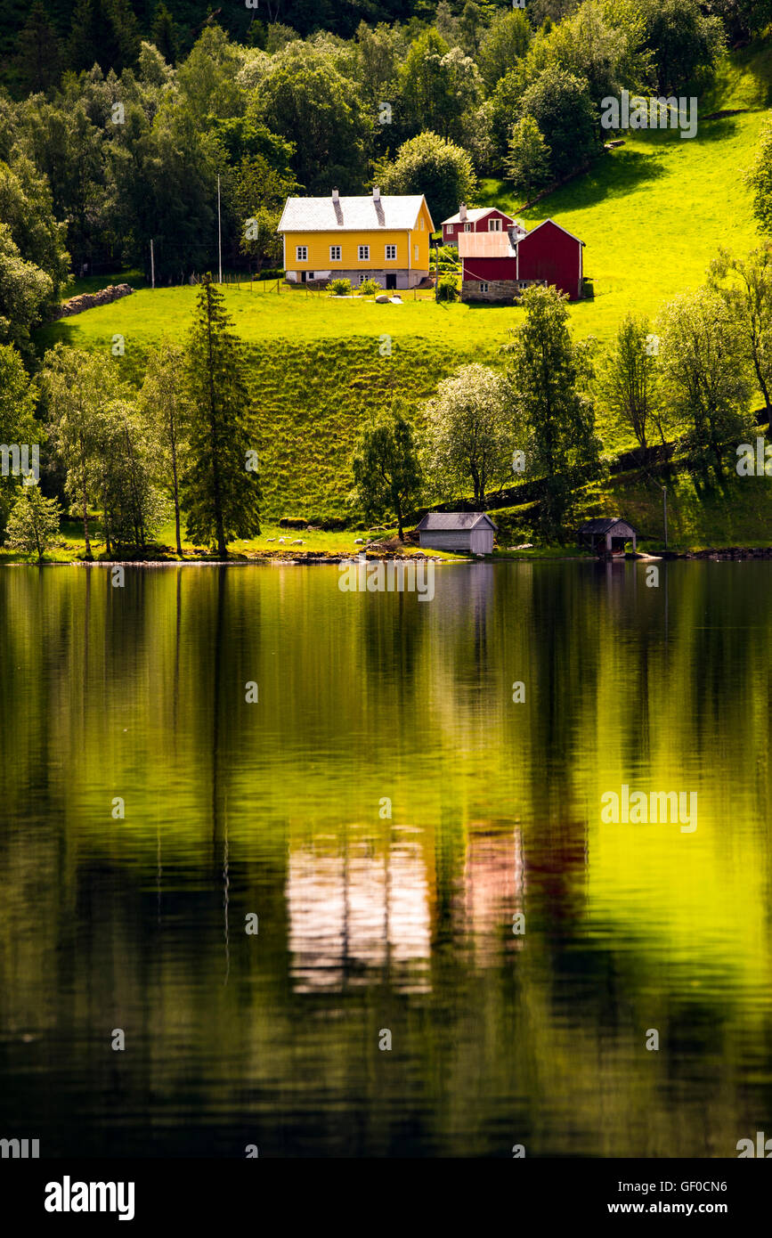 Colorful farm reflecting in mountain lake. Between Bergen and Alesund, Norway, Scandinavia, Europeam Stock Photo