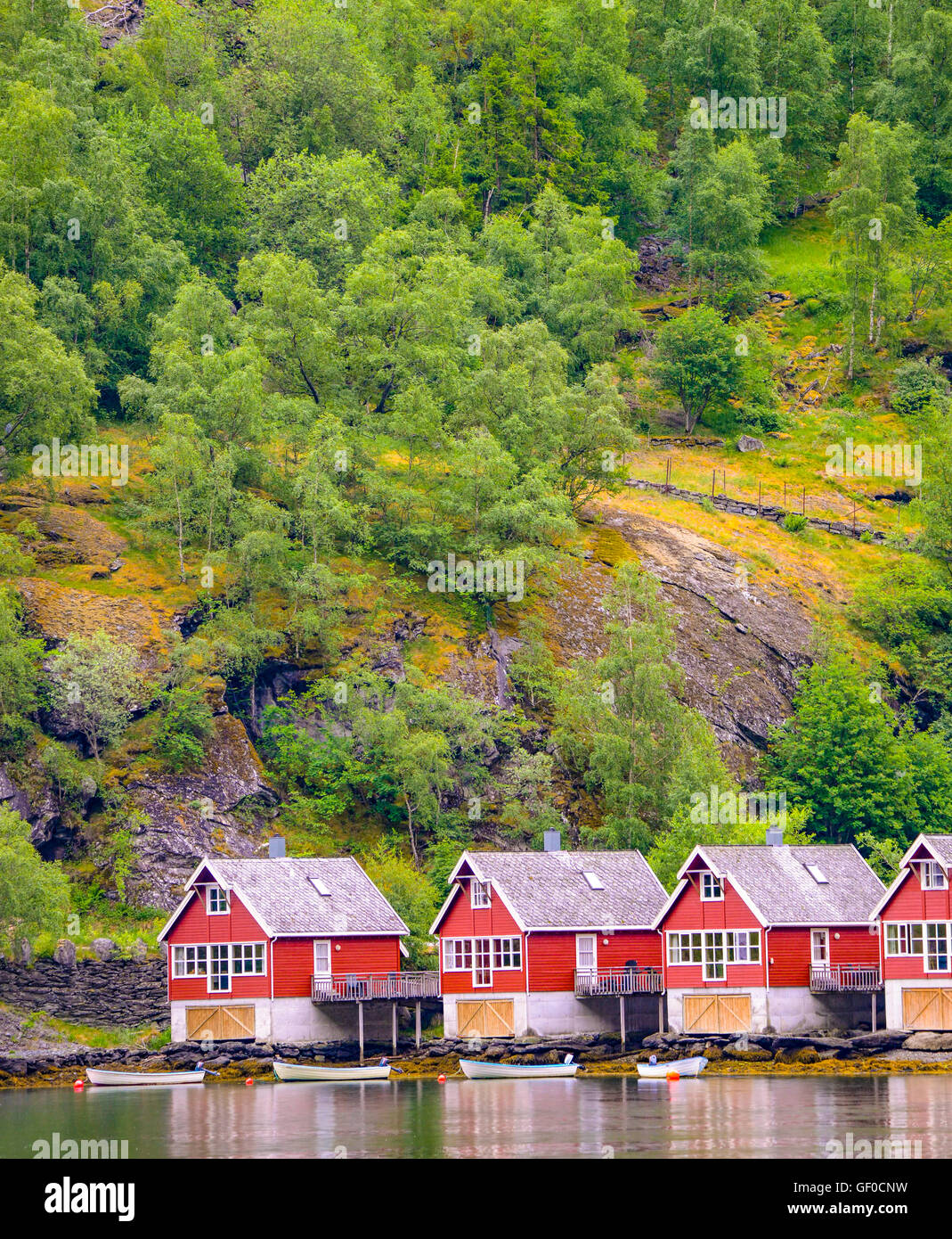 Fishermans huts and boats reflecting in Flam Harbour and Marina surrounded by mountain forest. Flam, Norway Stock Photo
